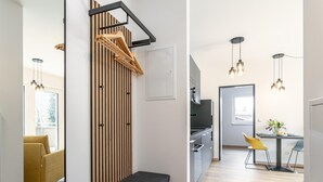 Una cocina moderna con horno empotrado, zona de comedor con mesa y sillas, y un banco con un estante de madera colgante.