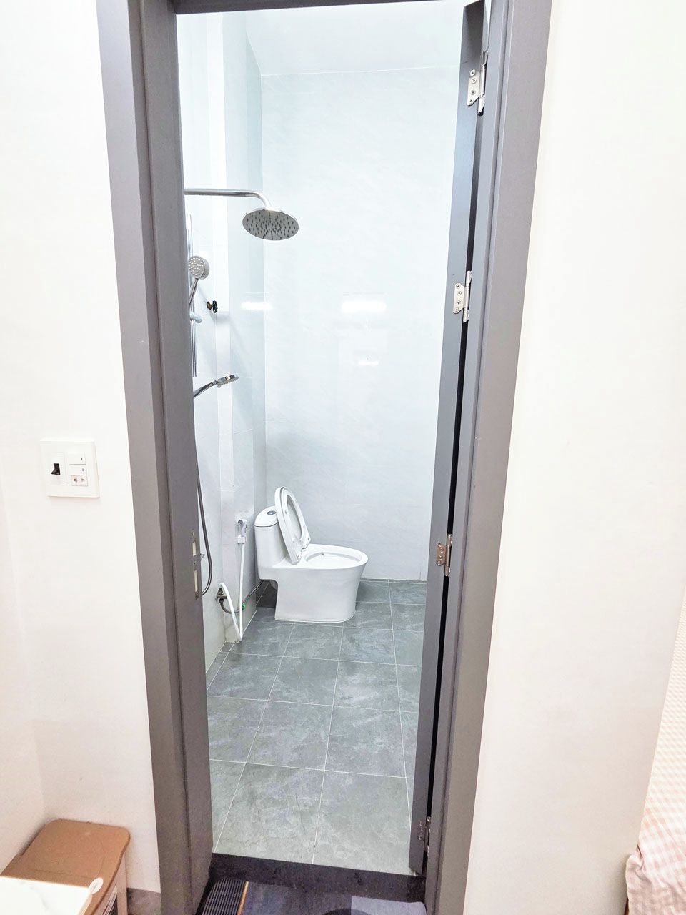 Un baño con ducha, inodoro y un escalón pequeño que da acceso a la zona de la ducha.