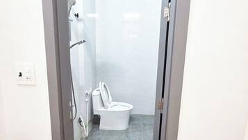 Un baño con ducha, inodoro y un escalón pequeño que da acceso a la zona de la ducha.