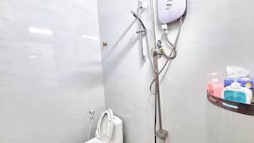 Ein Badezimmer mit Toilette, einer Dusche inklusive Handbrause und einem am Wand befestigten Wasserhahn.