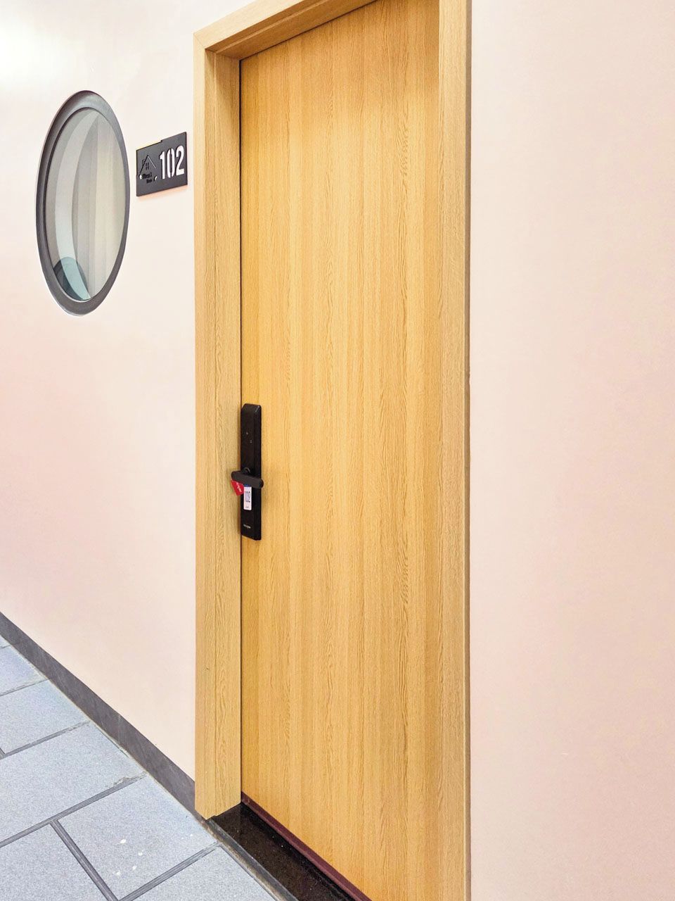 A wooden door with a digital lock and a number plate indicating room 102.