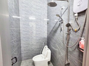 A bathroom with a shower, toilet, and a hand dryer.