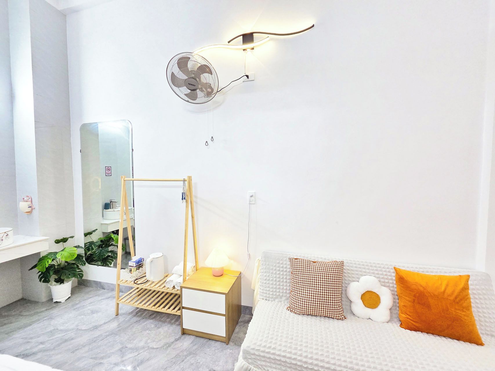 Un dormitorio moderno con cama, mesita de noche, lámpara y ventilador de pared.