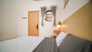 Una camera da letto con un letto, un comodino con una lampada, una porta e una finestra con tende.