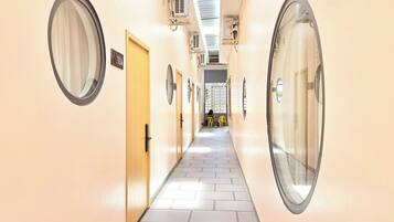 Un couloir d’hôtel avec des miroirs ronds, des portes et un sol carrelé.