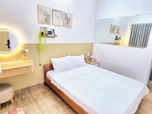 Une chambre d’hôtel comprenant un lit, une table de chevet, une lampe, un miroir et une œuvre d’art accrochée au mur.