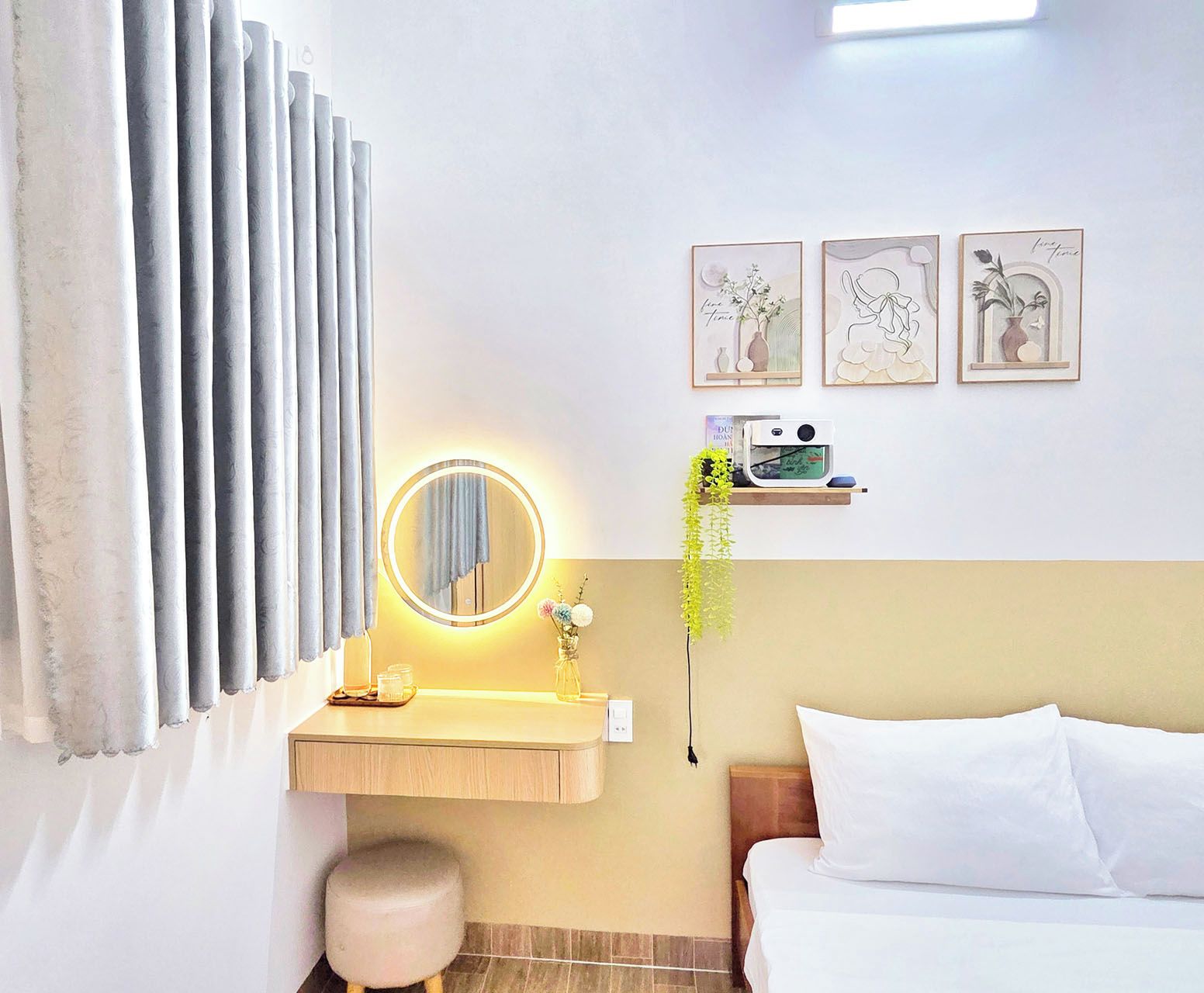 A hotel room with a bed, a bedside table with a lamp, a mirror, and a wall-mounted shelf with decorative items.