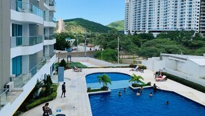Un immeuble résidentiel doté de nombreux balcons, d’une piscine et offrant une vue sur une colline.