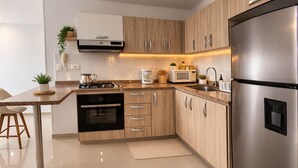 Une cuisine moderne dotée d’appareils électroménagers en acier inoxydable, de meubles en bois et d’un four encastré.