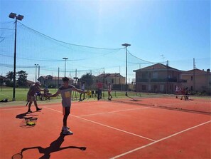 A tennis court with a net, players, and a basket of tennis balls. - Holiday apartment mit Pool (Loano)