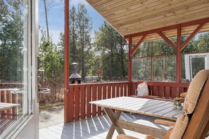 Une terrasse en bois avec une table et des chaises, une pergola en bois et une vue sur les arbres.