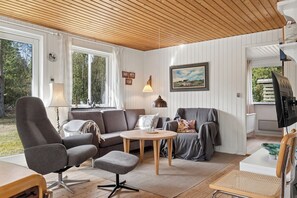 A cozy living room with a sofa, armchair, round table, and a television. - Experience the calm home near sea and forest (Hadsund)