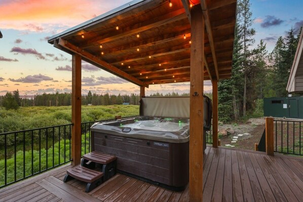 A hot tub on a wooden deck with a view of a forested landscape. - Creek Cabin | Private Creekside Cabin w/ Sauna, Hot tub, Trail Access & More! (Island Park)