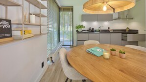 A modern kitchen with a round wooden table, built-in cabinets, and a hanging light fixture.