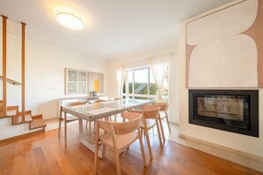 Een moderne keuken met een inbouwoven en een eethoek met een glazen tafel en houten stoelen.
