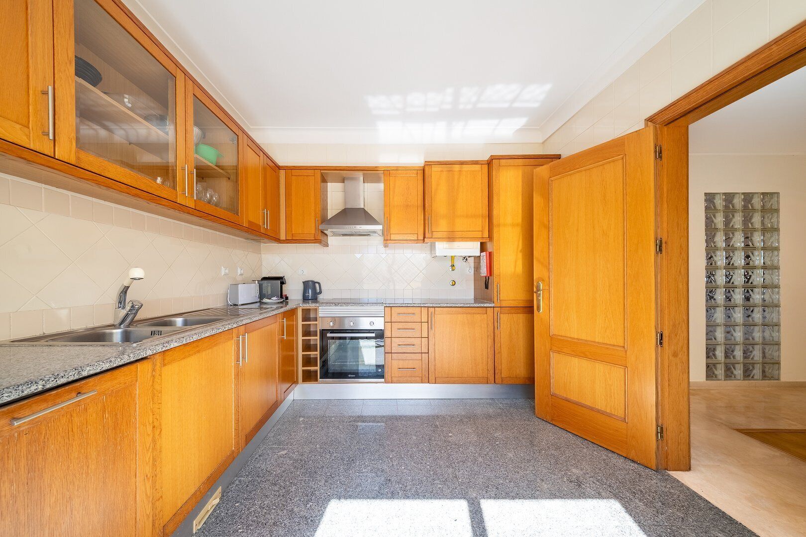 Una cocina con armarios de madera, un lavamanos de acero inoxidable, un horno empotrado y un microondas.