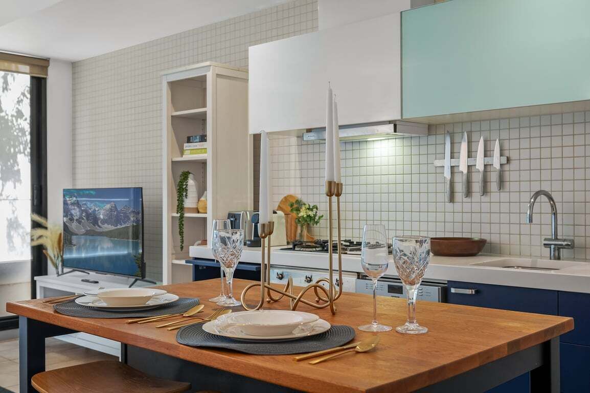 Une cuisine moderne avec une table à manger pour deux personnes, un téléviseur et une grande fenêtre.