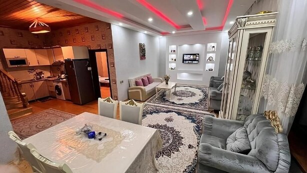A living room with a sofa, a dining table, and a kitchen in the background. - Gabala Dreams (Gabala)