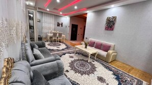 A modern living room with a grey sofa, a beige sofa, a coffee table, and a patterned rug. - Gabala Dreams (Gabala)