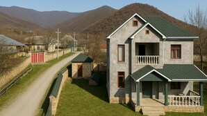 A two-story house with a green roof, a balcony, and a stone wall. - Gabala Dreams (Gabala)