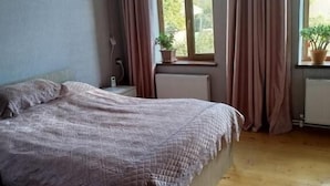 A bedroom with a bed, wooden floor, window with curtains, and a radiator. - Gabala Dreams (Gabala)