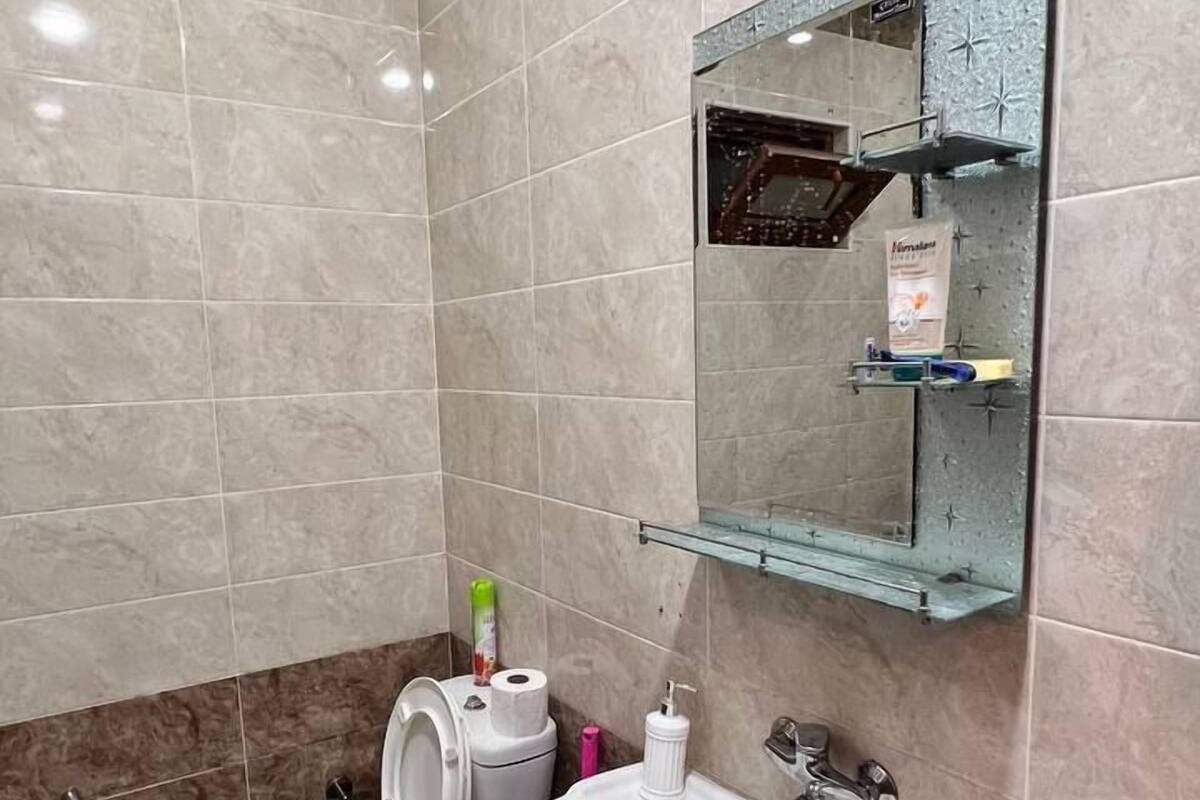A bathroom with a toilet, sink, and mirror.