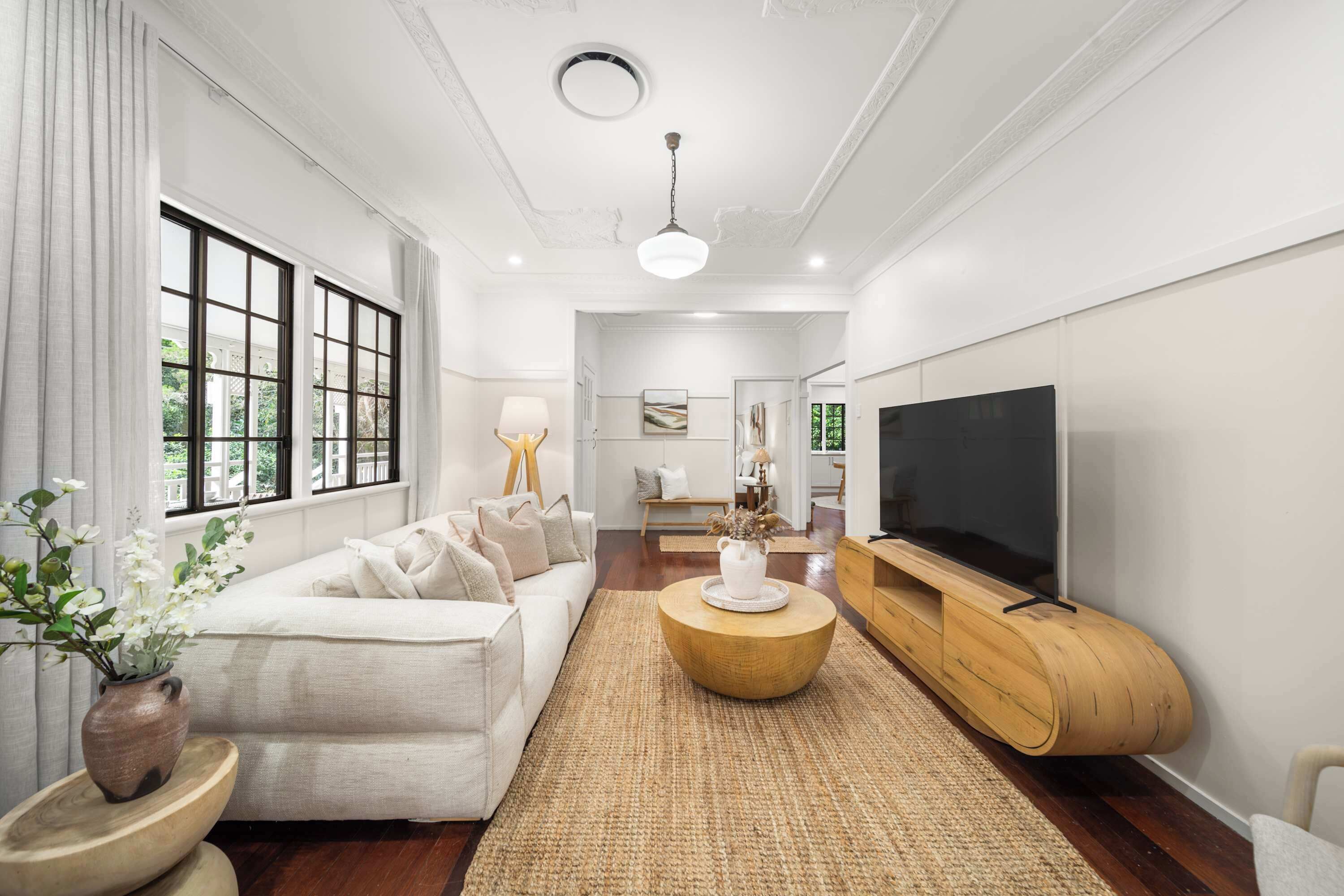 A modern living room with a sofa, coffee table, TV, and decorative plants.