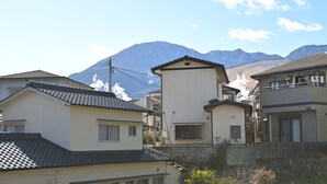 A residential area with houses, a small tower-like structure, and a mountain in the background. - Private Onsen House in Beppu - Spacious Stay for Families & 3 + Nights (別府市鉄輪)