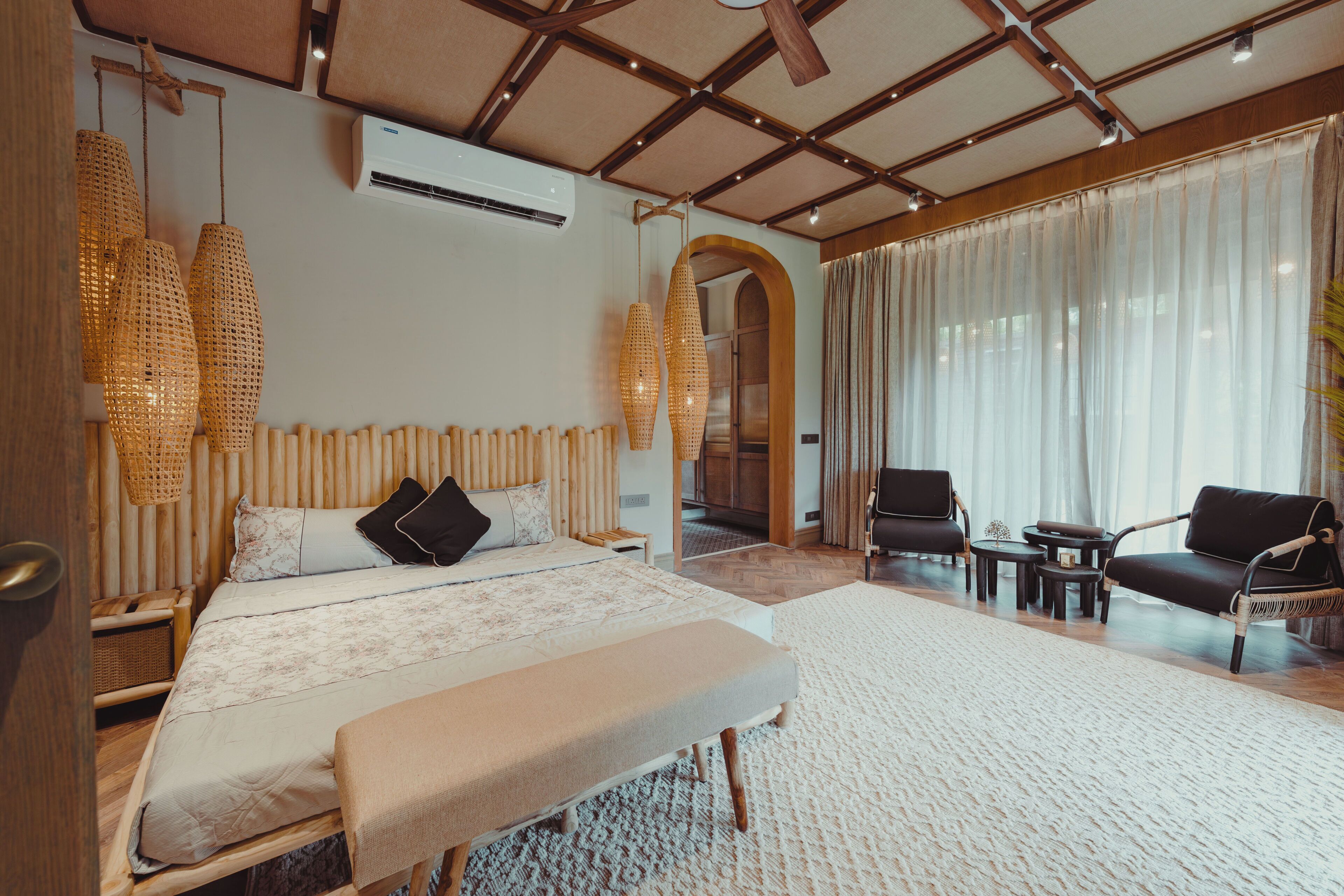 Een slaapkamer met een bed, nachtkastjes, een bankje, een sofa en een zithoek met stoelen.