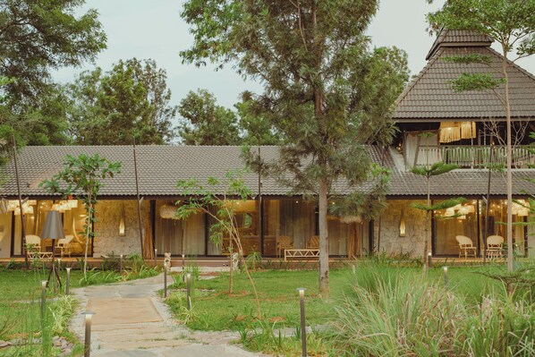 A two-story building with a stone facade, large windows, and a covered outdoor seating area.