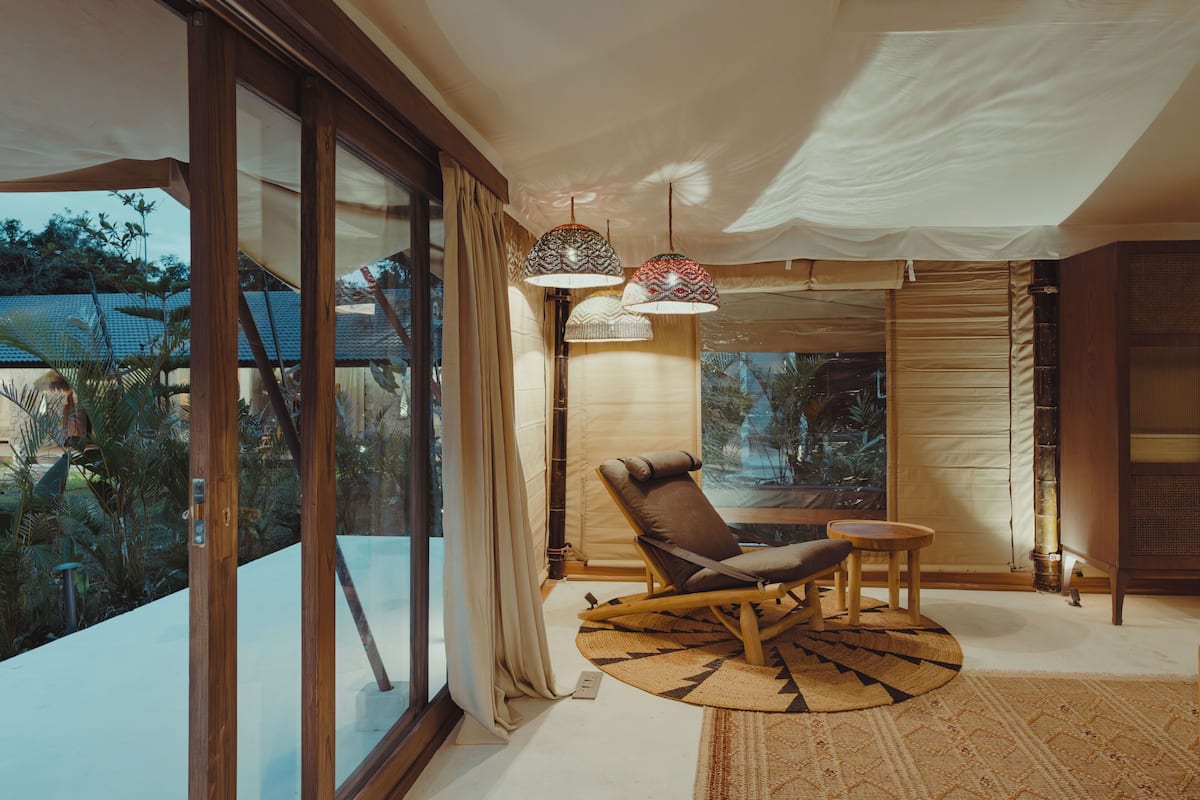 Een modern interieur met een grote schuifdeur, een rieten schommelstoel, een kleine tafel en twee hanglampen.