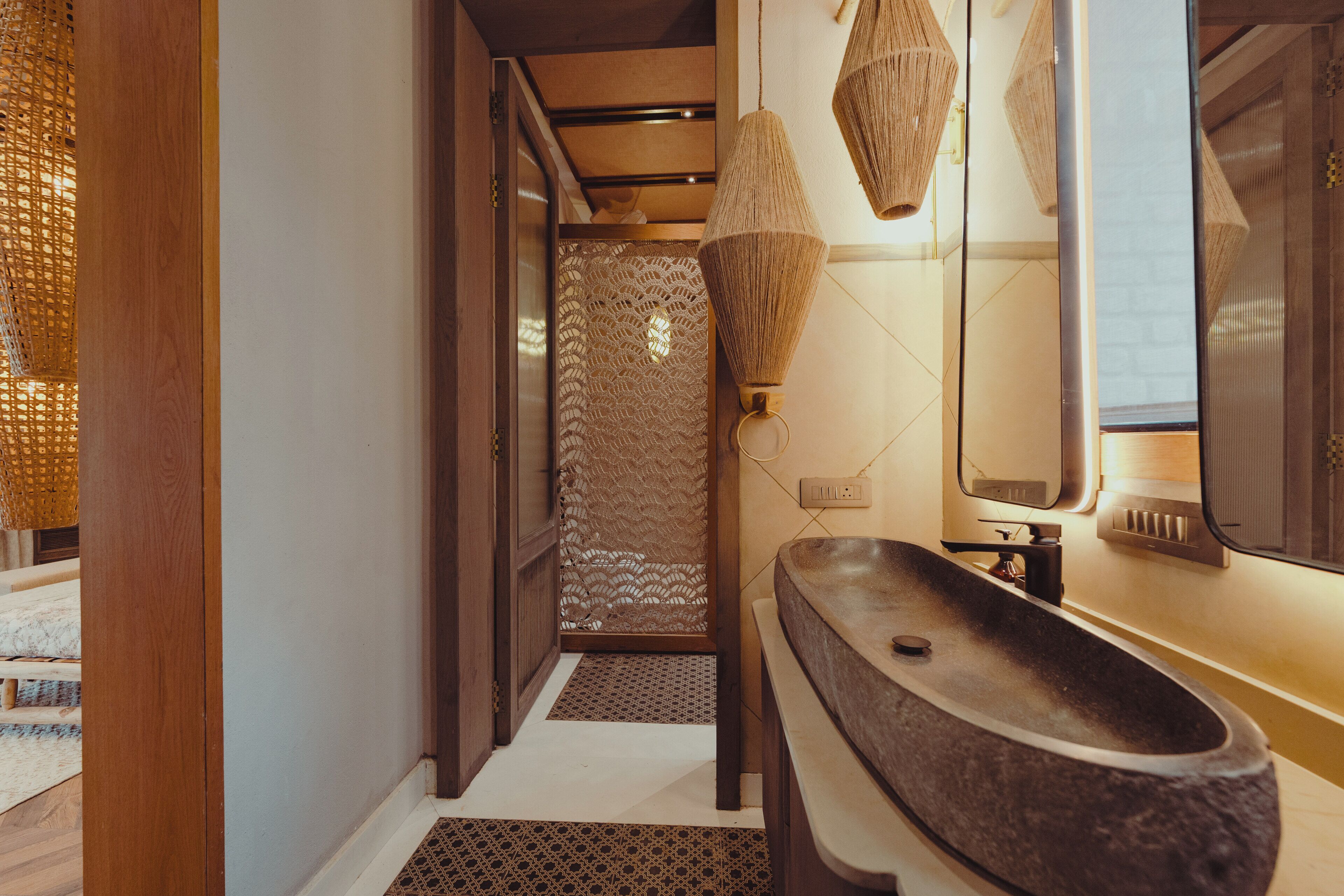 A modern bathroom with a stone sink, a mirror, and a textured wall.