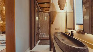 A modern bathroom with a stone sink, a mirror, and a textured wall.
