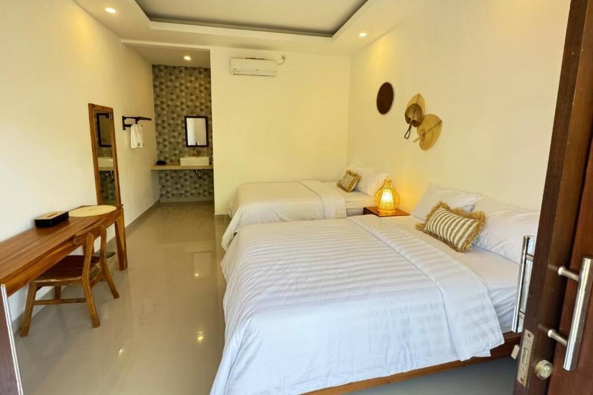 A hotel room with a bed, bedside table, and a desk with a chair.