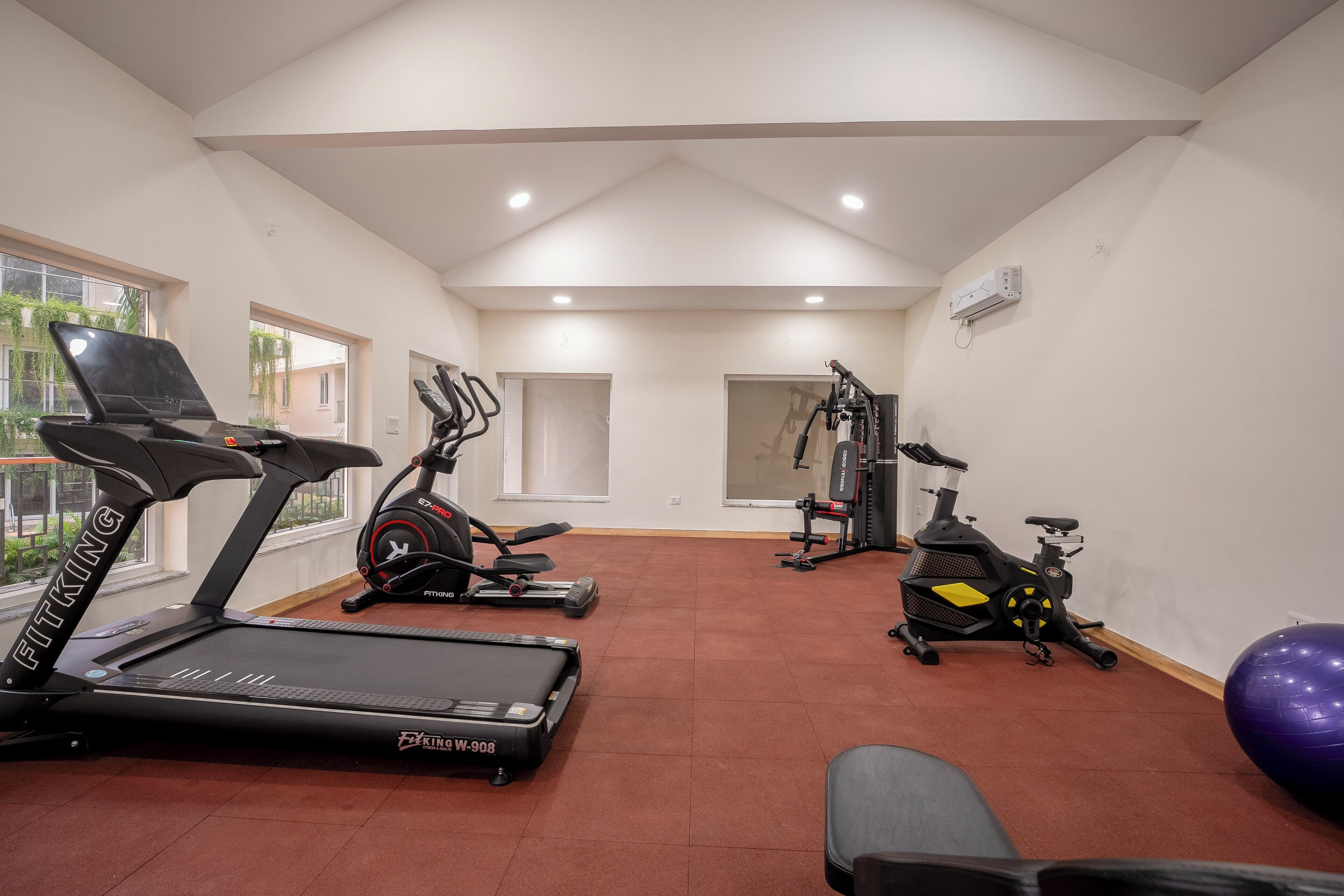 Un gimnasio con cintas de correr, bicicletas estáticas y pelotas de ejercicios.