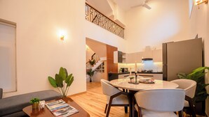 A modern living room with a dining area, a staircase, and a kitchen. - Staymaster Terra Nusa 4BR Villa (Colvale)