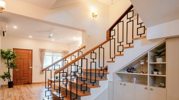 A staircase with geometric railings, wooden steps, and a white wall with built-in cabinets. - Staymaster Terra Nusa 4BR Villa (Colvale)