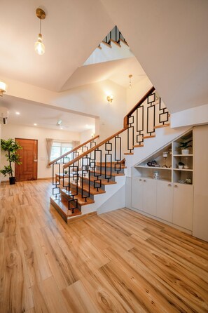 A staircase with geometric railings, wooden steps, and a white wall with built-in cabinets. - Staymaster Terra Nusa 4BR Villa (Colvale)