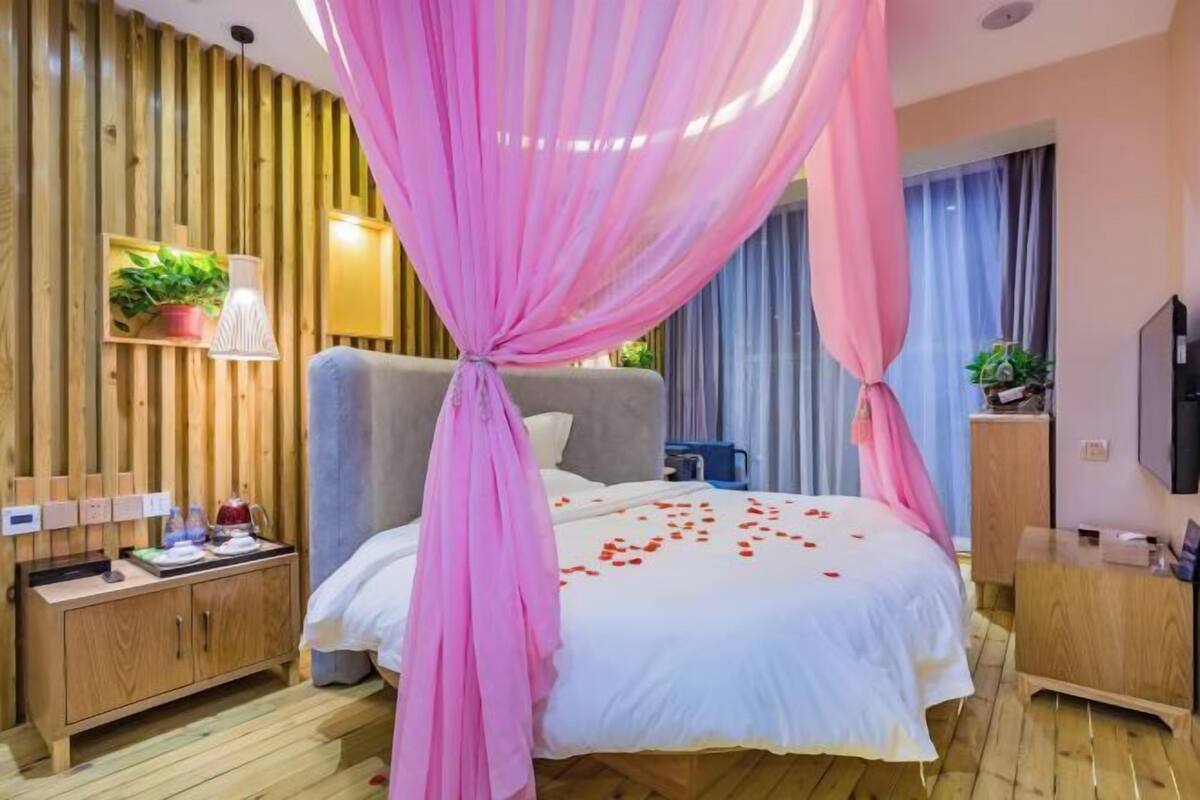 A bedroom with a bed, wooden panel wall, bedside table, and a TV.