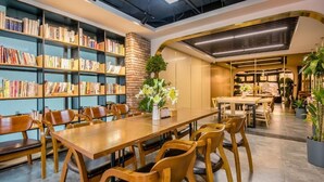 Une bibliothèque moderne dotée d’étagères, d’une grande table en bois au centre et de sièges confortables.