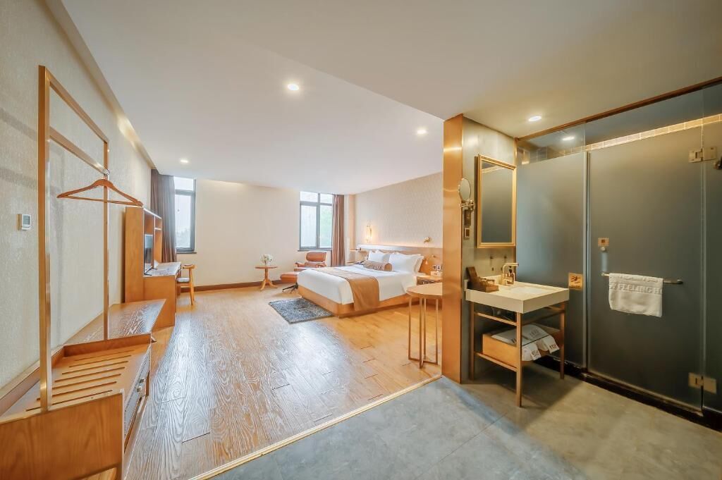A modern hotel room with a large bed, a desk, a vanity, and a walk-in closet.