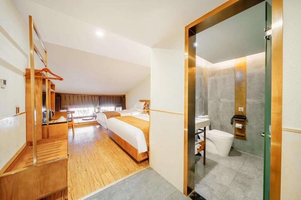A hotel room with a wooden staircase, a large bed, a bathroom with a glass shower enclosure, and a view of the outdoors.