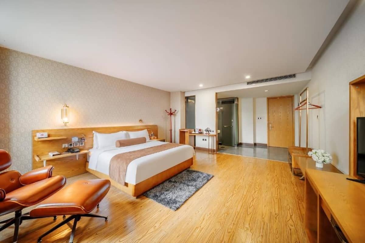 A hotel room with a bed, desk, chair, and a TV.