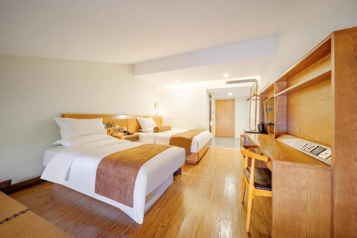 A hotel room with two beds, a desk, and a wardrobe.