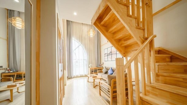 Un vaste espace de vie agrémenté d’un escalier en bois, d’un coin repas et d’une grande fenêtre laissant entrer la lumière naturelle.