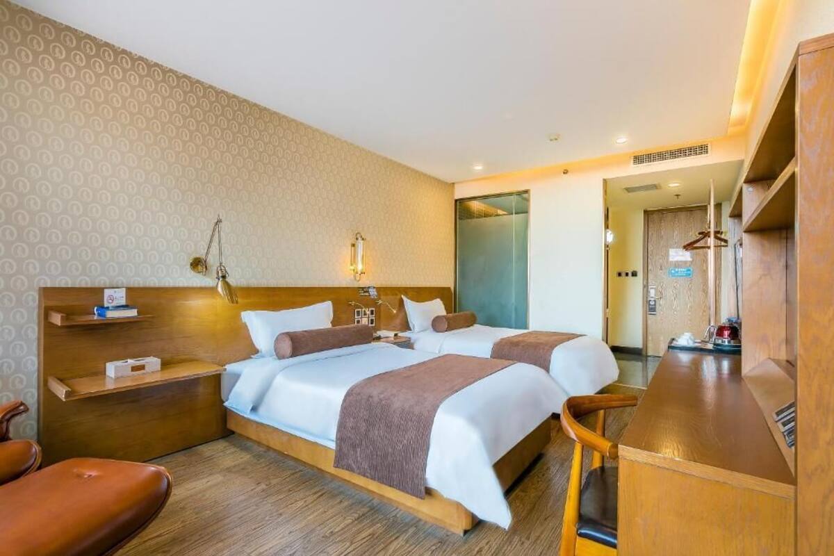 A hotel room with a large bed, bedside tables, a desk, and a mirror.