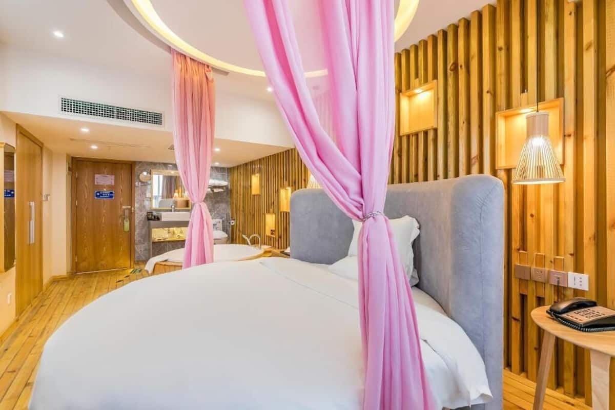 A hotel room with a large bed, a wooden wall panel, a bedside table, and a phone.