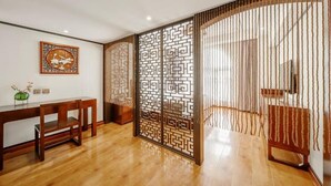 Une pièce avec un bureau en bois, un paravent décoratif et une œuvre d’art encadrée accrochée au mur.