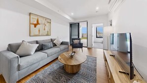 Ein modernes Wohnzimmer mit einem grauen Sofa, einem Couchtisch, einem Fernseher und einem Gemälde an der Wand.
