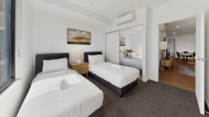 Ein Hotelzimmer mit zwei Betten, einem Gemälde, einem Spiegel und Blick auf den Speisesaal.